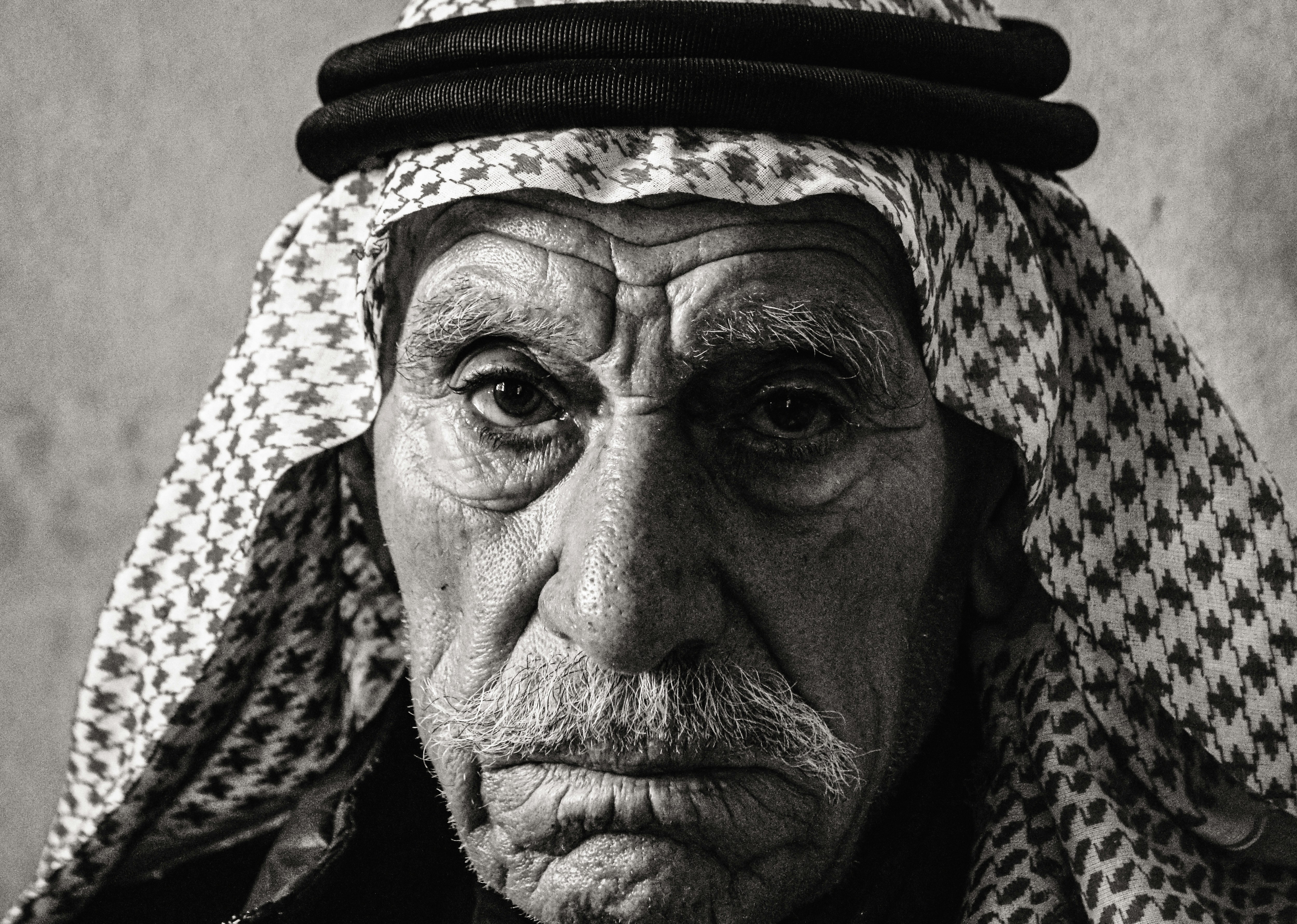 a black and white photo of an old man wearing a hat